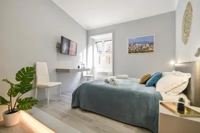 a white bedroom with a bed and a desk at Suite 109 in Rome