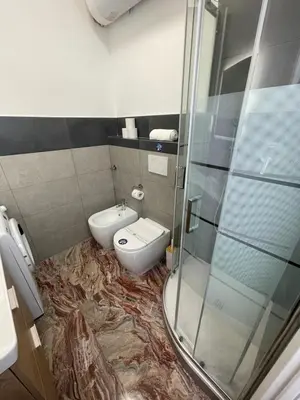 a bathroom with a toilet and a glass shower at Henry Suite in Rome