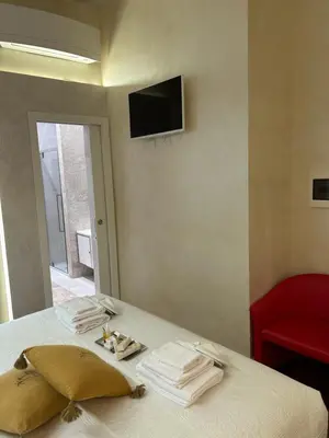 a bedroom with a bed with towels and a tv on the wall at Piazza Venezia Luxury Suite in Rome
