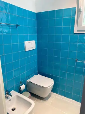 a blue tiled bathroom with a toilet and a sink at Villette Aldobrandeschi Urban Oasis Vacation Homes in Rome