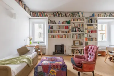 a living room with a couch and chairs and bookshelves at iFlat The Carpet Apartment in Rome