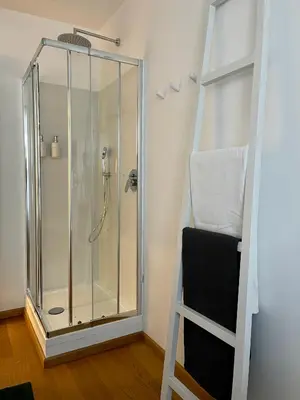 a glass shower in a room with a black chair at Garden house in Rome