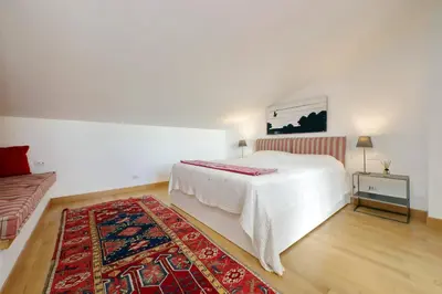 a white bedroom with a bed and a rug at Beautiful Loft in Ponte Milvio with terrace in Rome