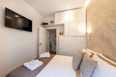 a bedroom with a bed and a tv and white cabinets at Barcaccia Exclusive apartment in Rome