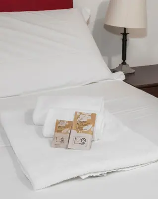 a white bed with towels and two boxes on it at Suites Campo de' Fiori - Zen18-19-20 in Rome