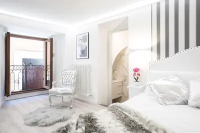 a white bedroom with a bed and a chair at My Piazza Navona Jacuzzi Suite - Top Collection in Rome