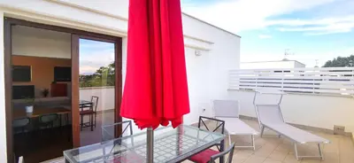 a glass table and chairs on a balcony with a red umbrella at Cosy penthouse loft with stunning view in Rome