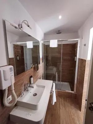 a bathroom with a white sink and a shower at MICHELANGELO SUITE ROMA GUEST HOUSE camere con vista sulle Terme di Diocleziano e sul Chiostro di Michelangelo in Rome