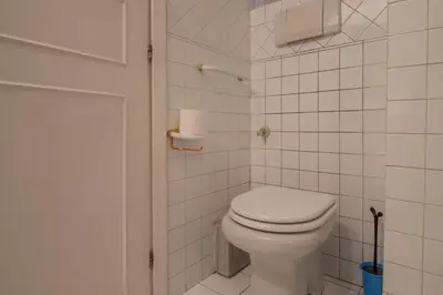 a bathroom with a toilet and a white tiled wall at Praty Rooms in Rome