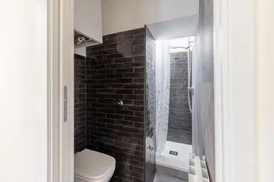 a bathroom with a toilet and a black brick wall at iFlat The Heart of Monti in Rome