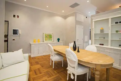 a dining room with a wooden table and white chairs at FORNACI 48 GUEST HOUSE in Rome