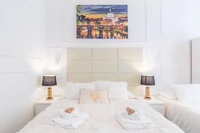 a white bedroom with two beds and two lamps at Glint House Roma Sapienza in Rome