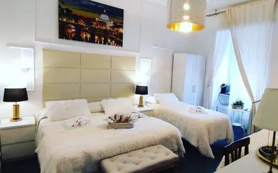 a bedroom with two beds and a table and lamps at Glint House Roma Sapienza in Rome