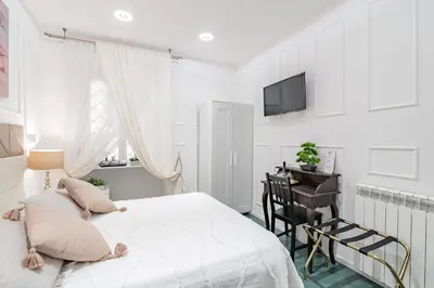 a white bedroom with a bed and a desk at Glint House Roma Sapienza in Rome