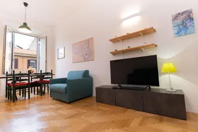 a living room with a television and a blue chair at Scipioni Holiday House in Rome
