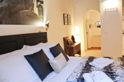 a bedroom with a bed with white sheets and a chair at Sophisticated Studio Decor in Rome