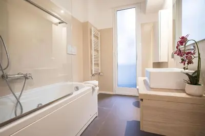 a white bathroom with a tub and a sink at My Trastevere Three Bedroom View Apartment in Rome