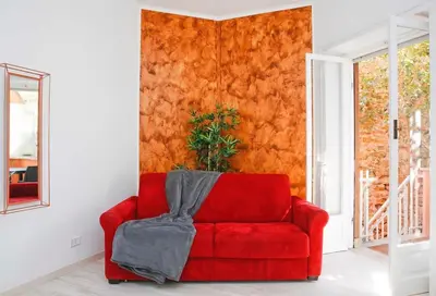 a red couch in a room with an orange wall at Charming Patio Apartment Trastevere in Rome