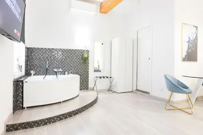 a white bathroom with a tub and a chair at Trastevere Silver King Jacuzzi Suite in Rome