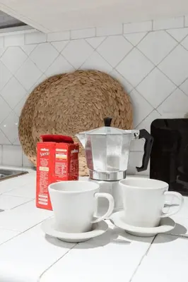 two white coffee cups on a counter with a juicer at Decor Inspiration Apartment in Rome