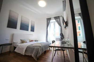 a white bedroom with a bed and a table at Cosmo GuestHouse in Rome