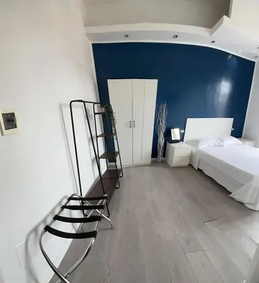 a bedroom with a white bed and a blue wall at Boutique Rooms in Rome