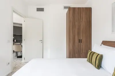 a bedroom with two white beds and a wooden cabinet at Numa Rome Verso in Rome