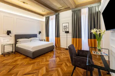 a bedroom with a bed and a desk and a chair at Largo Arenula Suites in Rome