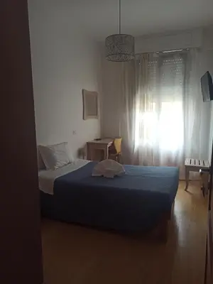 a bedroom with a bed with a blue blanket and a window at B&B Suite and Rooms San Giovanni in Rome