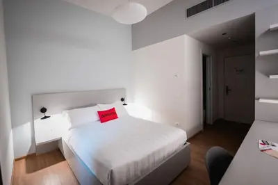 a bedroom with a white bed with a red pillow at Dotcampus Roma City Center in Rome