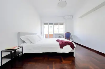 a white bedroom with a bed and a blue chair at Vatican Charme in Rome