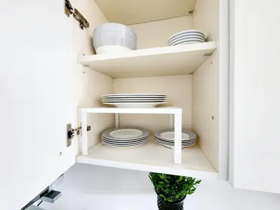 a white pantry with plates and dishes on shelves at Quela Apartment - Pietralata in Rome