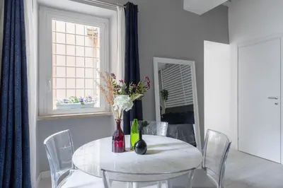 a white dining room table with chairs and a vase with flowers at iFlat The G Flat in Rome
