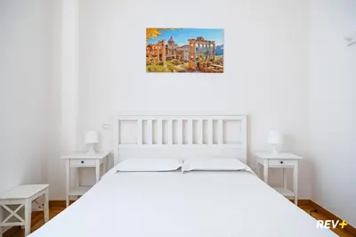 a white bedroom with a white bed and two tables at Mecenate Apartment Colosseum in Rome
