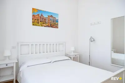 a white bedroom with a white bed and a bathroom at Mecenate Apartment Colosseum in Rome