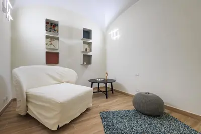 a living room with a white chair and a rug at Mater Rooms & Suites in Rome