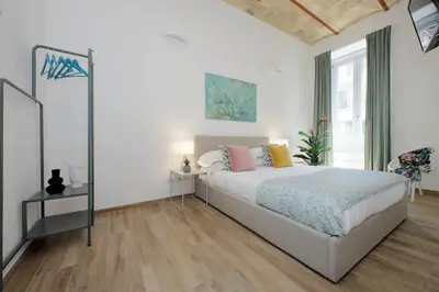 a white bedroom with a bed and a large window at Principe Umberto Apartment in Rome