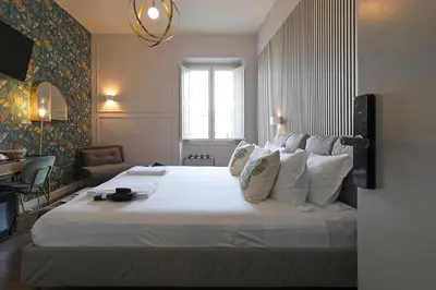 a bedroom with a large bed with white sheets and pillows at Rome Plaza Suites, Luxury Collection in Rome