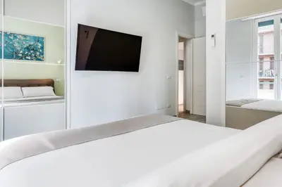a white room with a bed and a flat screen tv at Re di Roma Apartment in Rome