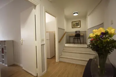 a hallway with stairs and a table with a vase of flowers at Vascello Holiday House in Rome