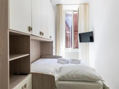 a small bedroom with a bed and a tv at FCR Rome Apartments Gracchi Vatican in Rome