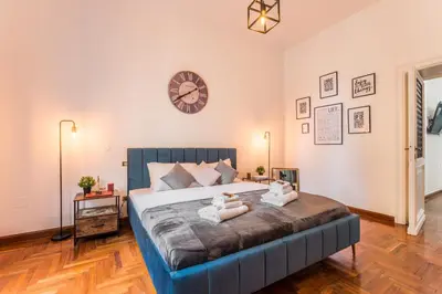 a bedroom with a large bed with a clock on the wall at Appartamento Principe Amedeo in Rome