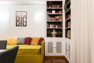 a living room with a yellow couch in a book shelf at Appartamento Principe Amedeo in Rome