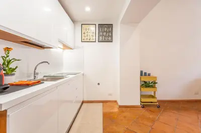 a kitchen with white cabinets and a sink at Barberini 3 BDR Apartment in Rome