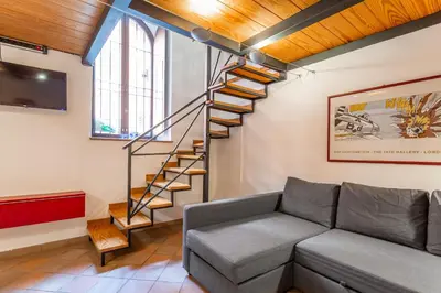 a living room with a couch and a spiral staircase at Trastevere Vintage Artistic Loft in Rome