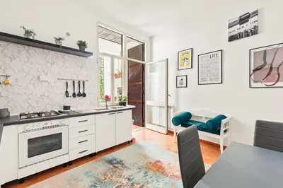 a kitchen with white cabinets and a table and a couch at R.C. Cappellari Loft Campo de' Fiori in Rome