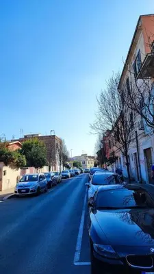 a street with cars parked on the side of the road at l'altra casetta dei Quintili in Rome