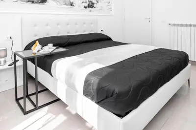 a white bedroom with a large bed with a black blanket at Emperooms Guest House in Rome