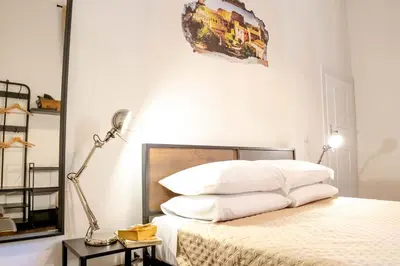 a bedroom with a bed with white sheets and a lamp at MyWay Colosseo Apartment in Rome
