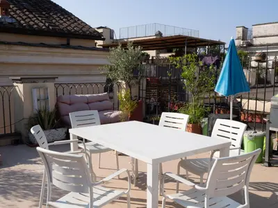 a white table and chairs and a blue umbrella at Terrace Apartment On The Monuments Of Rome in Rome